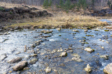 autumn morning, walking along the bed of a mountain river that has become shallow by the beginning of the winter period and exposing its rocky bottom.