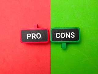 Colored wooden board with word PRO and CONS on a colorful background. Business concept.