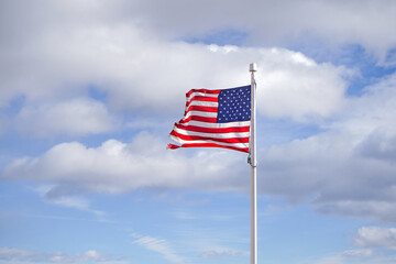 American flag on the background of a blue sky with clouds.