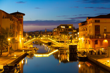 Twilight in Frejus, South of France. View of Buildings and bridge across Reyran River illuminated by city lights.