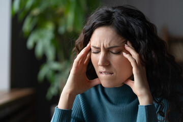 Closeup of unhappy stressed woman suffering from tension-type headache triggered by stress,...
