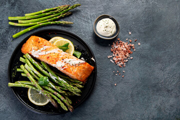 Baked salmon with asparagus on gray background.