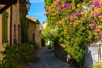 Scenic view of medieval Provencal village of Grimaud with ancient stone buildings on narrow flowering cobbled streets on sunny fall day, France.