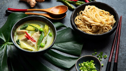 Green curry with chicken in bowl on dark background.