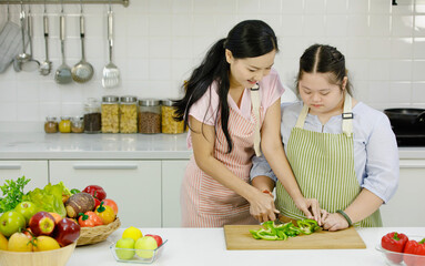 Asian young chubby down syndrome autistic daughter wears apron hugging cuddling showing love to...