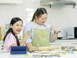 Asian young happy chubby down syndrome autistic daughter wears apron standing smiling laughing in...