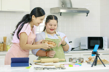 Asian young happy chubby down syndrome autistic daughter wears apron standing smiling laughing in...