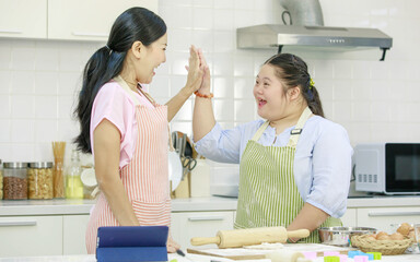 Asian young happy chubby down syndrome autistic daughter wears apron standing smiling laughing in...