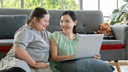 Portrait shot of Asian lovely mother sitting on floor and young chubby down syndrome autistic...