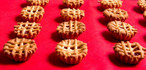 Cookies with red jam and tablecloth close-up, top view, copy space, pattern