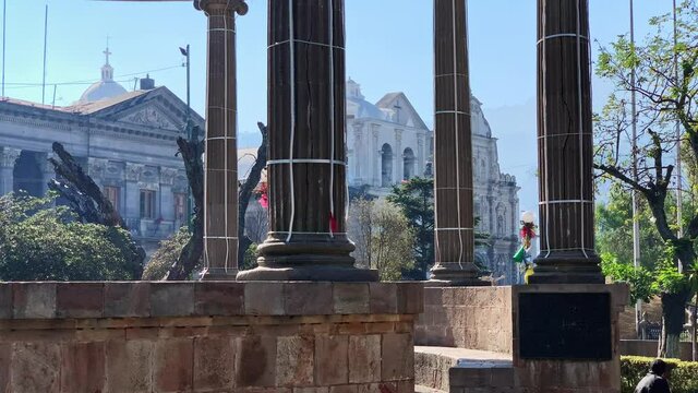 Neoclassical Columns Structure With Church In The Background In Central American Guatemalan City Center Park. Parque Central Quetzaltenango Xela Guatemala.