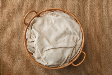 Round wicker basket with a blanket for newborns on a  vintage carpet