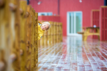 Cute child, enjoying little fishing village with rorbuer cabins on heavy rainy day