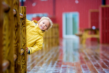Cute child, enjoying little fishing village with rorbuer cabins on heavy rainy day