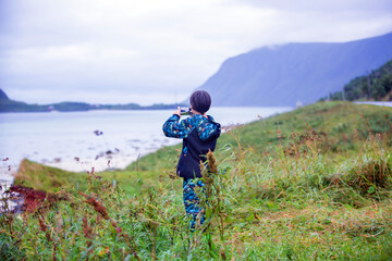 Cute child, taking picture of white sand beach in the summer on Lofoten, Norway