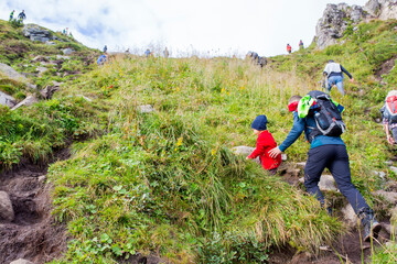 Children, toddler, brothers and father, climbing the stairs to Reinebringen, trekking path leading to the top of the mountain, where one can see Reine village and many fjords