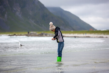 Cute child, running on norwegian white sand beach in the summer, Norway - obrazy, fototapety, plakaty