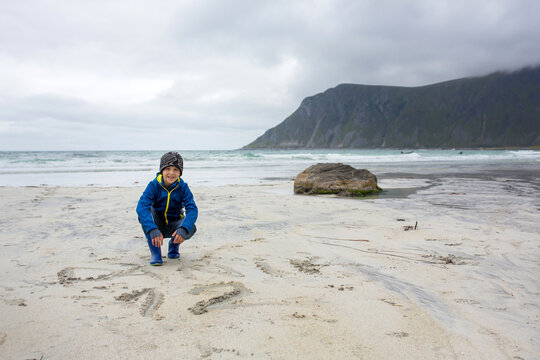 Cute child, running on norwegian white sand beach in the summer, Norway