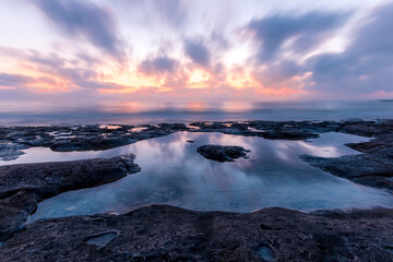 Twilight scenic sea landscape with beautiful shore, blurred flying dramatic blue clouds, amazing shoreline and sunset on background