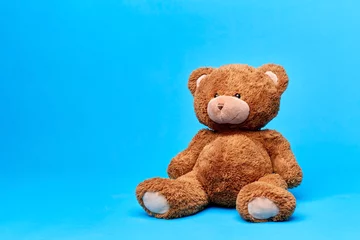 Fotobehang soft toys and childhood concept - brown teddy bear over blue background © Syda Productions