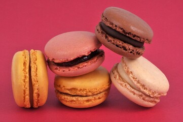 Macarons de différentes saveurs en gros plan sur fond rouge