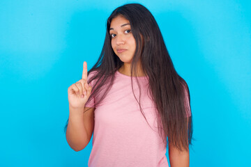 No sign gesture. Closeup portrait unhappy Young hispanic girl wearing pink T-shirt over blue...