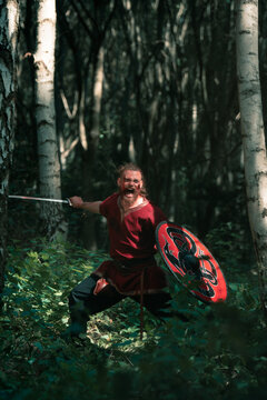 Aggressive viking with shield and sword fighting in forest