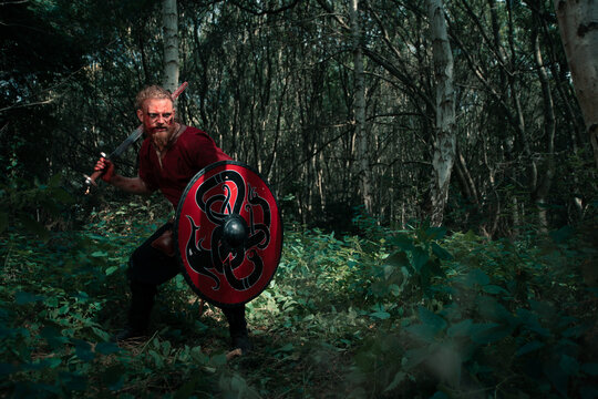 Aggressive viking with shield and sword fighting in forest