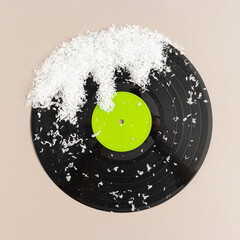 Minimal pop art holiday composition made with vinyl record with green label and snow against beige...