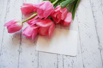 Beautiful color tulip flowers composition with blank card on white wooden table. floral background for Mother's day, Women's day, Easter and Spring time.