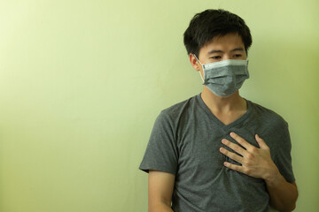 Infected Smart handsome young Asian man is touching chest to check symptoms about Coronavirus disease or Covid-19 at home, man feels bad and fear, he home quarantine to stop the spread of virus.