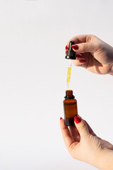 Woman dripping essential oil into bottle on white background, closeup, isolated