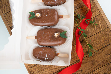 Festive dessert box. Chocolate cake pops in the form of ice cream on a stick on a wooden stand, top view. Concept food