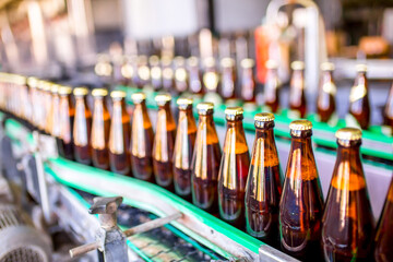 Brewery factory spilling beer into glass bottles on conveyor lines. Industrial work, automated production of food and drinks. Glass products. Bottles for drinks. Technological work at the factory.