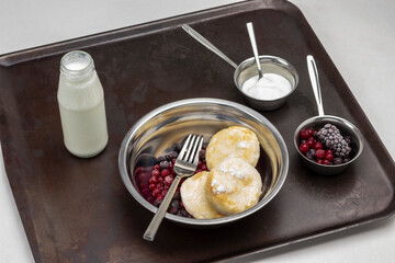 Cheesecakes with frozen berries and fork in metal plate.