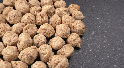 Raw soya chunks on dark background. Healthy, nutritious soybean meat, chunks isolated.Vegan food concept.