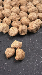 Raw soya chunks on dark background. Healthy, nutritious soybean meat, chunks isolated.Vegan food concept.