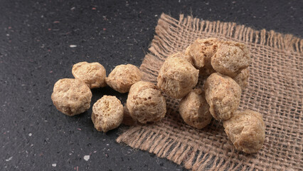 Raw soya chunks on dark background. Healthy, nutritious soybean meat, chunks isolated.Vegan food concept.