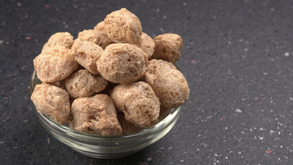 Raw soya chunks on dark background. Healthy, nutritious soybean meat, chunks isolated.Vegan food concept.