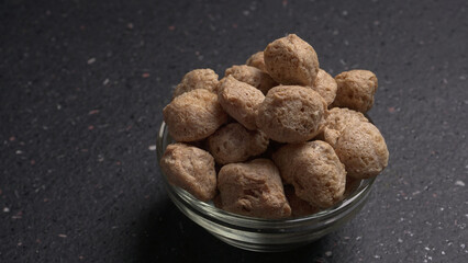 Raw soya chunks on dark background. Healthy, nutritious soybean meat, chunks isolated.Vegan food concept.
