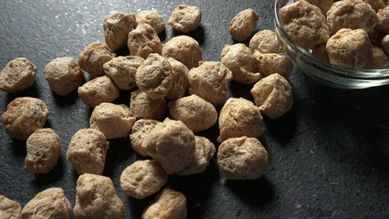 Raw soya chunks on dark background. Healthy, nutritious soybean meat, chunks isolated.Vegan food concept.