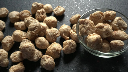Raw soya chunks on dark background. Healthy, nutritious soybean meat, chunks isolated.Vegan food concept.