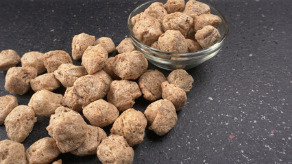Raw soya chunks on dark background. Healthy, nutritious soybean meat, chunks isolated.Vegan food concept.