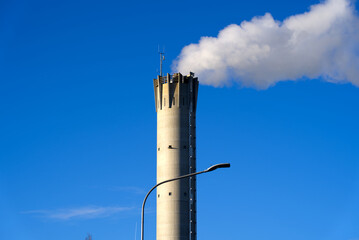 Chimney of waste incineration plant Hagenholz with white smoke and blue cloudy sky on a winter day at City of Zurich, Switzerland. Photo taken December 31st, 2021, Zurich, Switzerland.