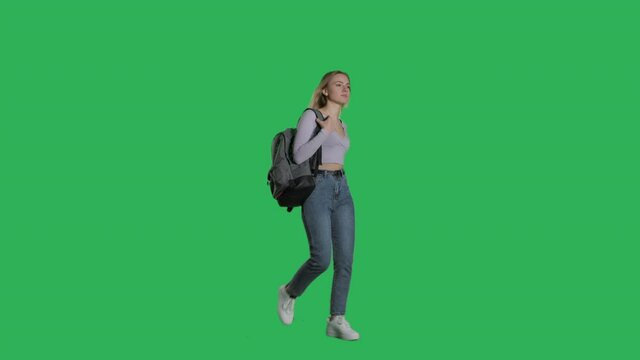 Happy young female model walking with backpack on a Green Screen, Chroma Key. 4k UHD perspective view isolated video.