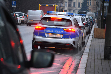 Policjanci ruchu drogowego polskiej policji w mieście podczas kontroli ruchu pojazdów. w odblaskowej kamizelce. 
