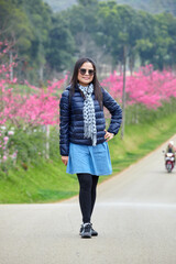 A woman in coat standing in the park on pink flower background