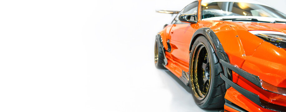 Front headlights of orange modify car on white background, copy space