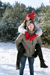 Guy rolls girl on his back. Loving young couple is having fun in winter outdoors.