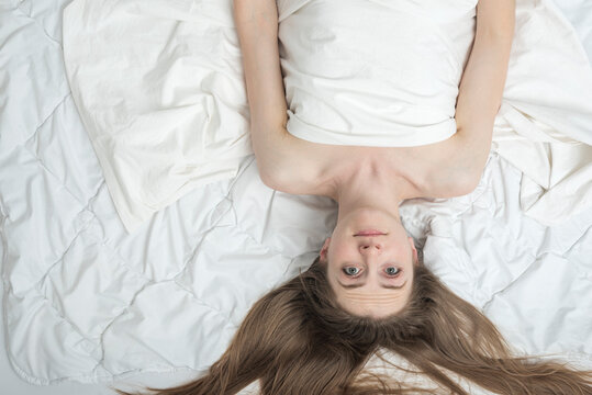 Young woman lies in bed with her eyes open. Insomnia. Sleep disorders. Girl cannot sleep. Copy space, top view